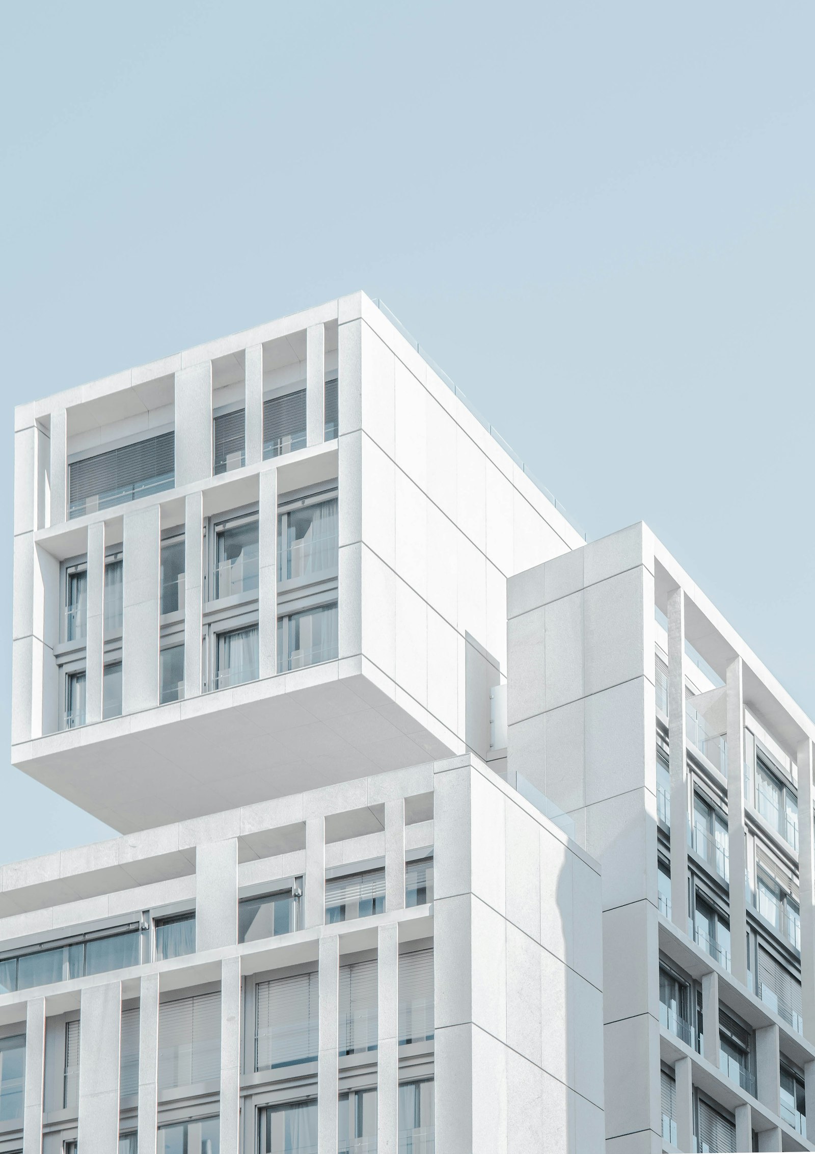 White modular residence of stacked, cantilevered volumes against a pale sky