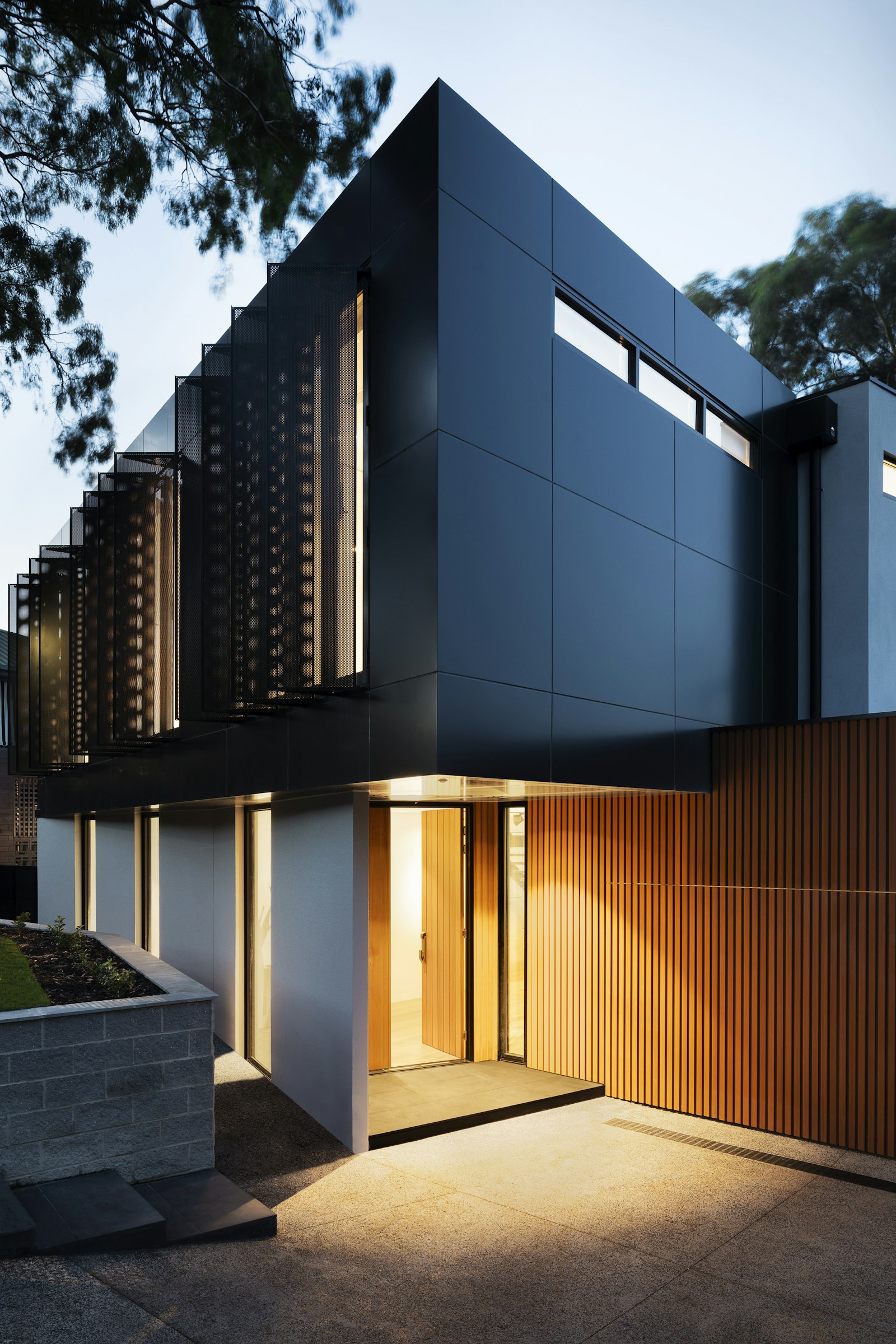 Detail of a dark facade with warm vertical wood slats at dusk