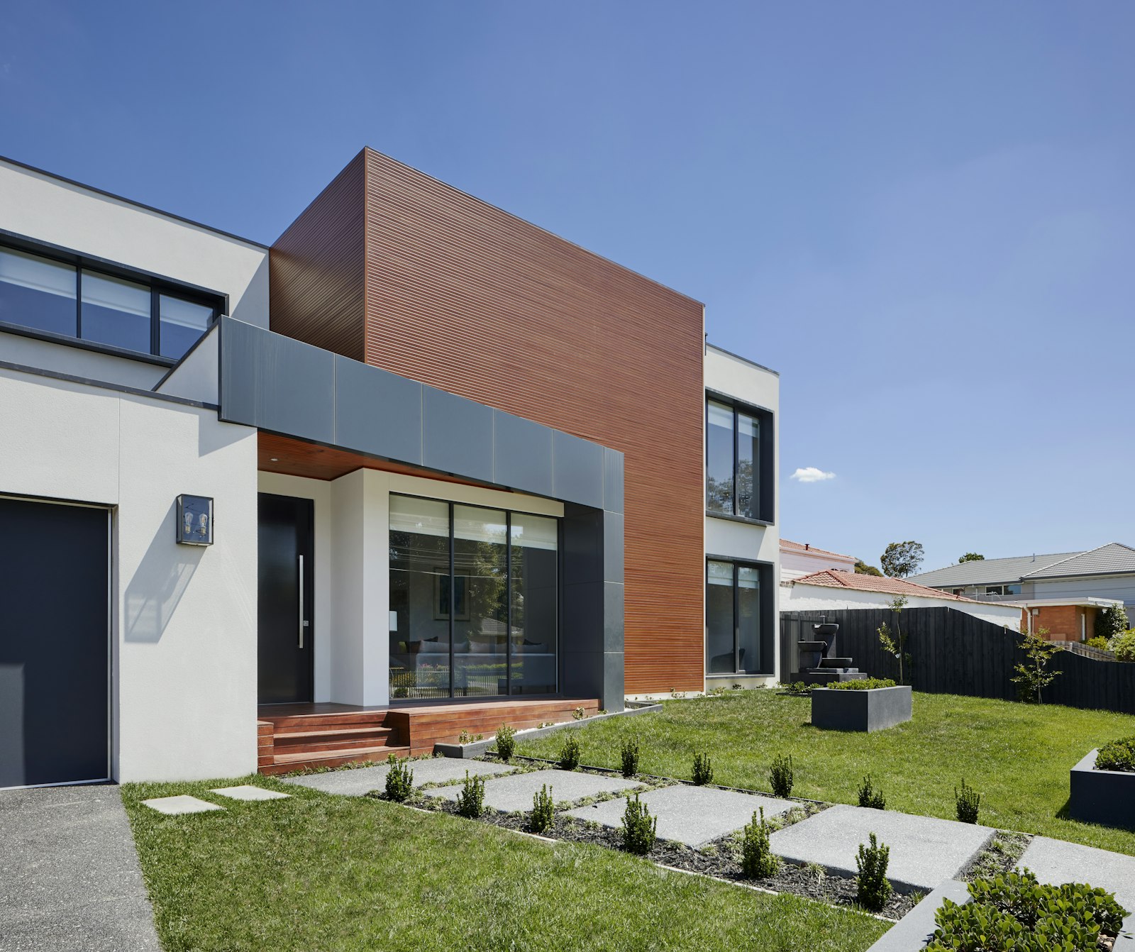 Contemporary home with copper-toned cladding and a manicured lawn